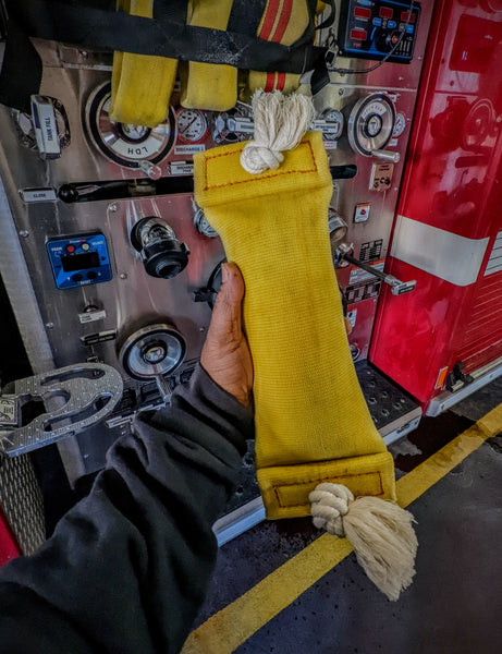 Water bottle-filled repurpose fire hose dog toy with knotted rope tassels. Interactive dog toy, American-made, durable , recycled, upcycled